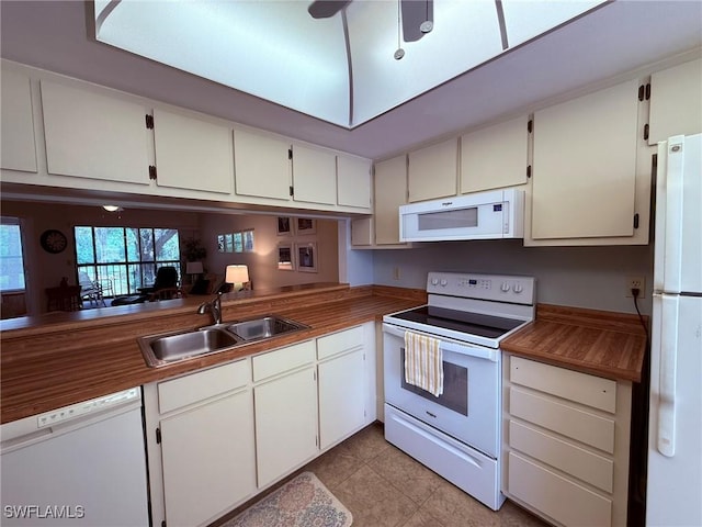kitchen featuring white appliances, light tile patterned floors, white cabinets, and a sink
