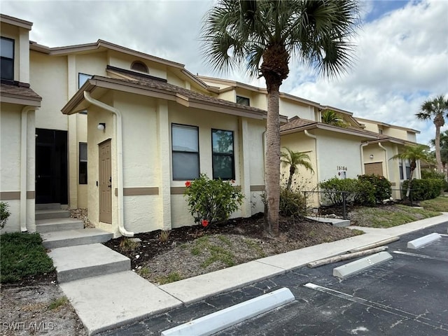 view of front facade with uncovered parking, entry steps, and stucco siding
