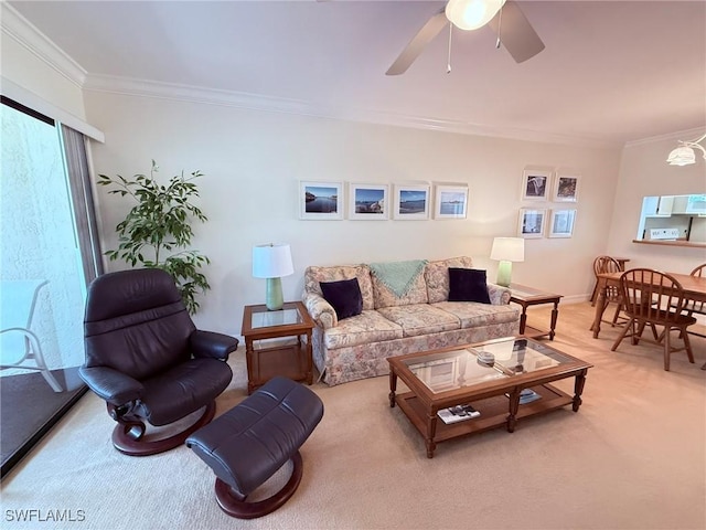 living area featuring crown molding, baseboards, a ceiling fan, and light colored carpet