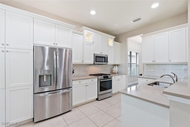 kitchen with appliances with stainless steel finishes, decorative backsplash, a sink, and visible vents