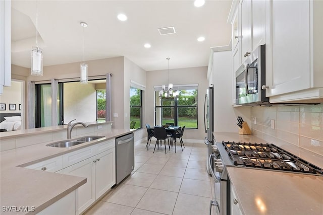 kitchen with decorative backsplash, visible vents, appliances with stainless steel finishes, a sink, and light countertops