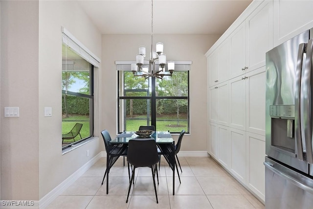 dining area featuring an inviting chandelier, baseboards, and light tile patterned flooring
