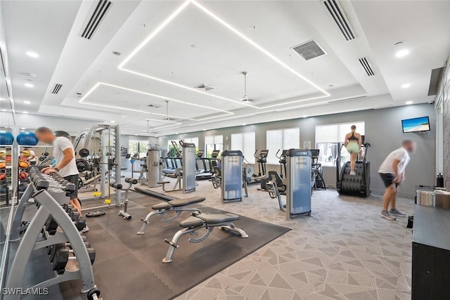workout area featuring a tray ceiling, visible vents, and plenty of natural light