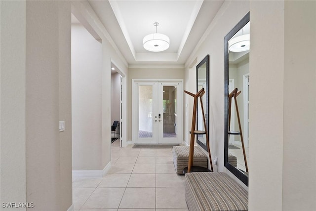 interior space with french doors, baseboards, light tile patterned flooring, and a tray ceiling