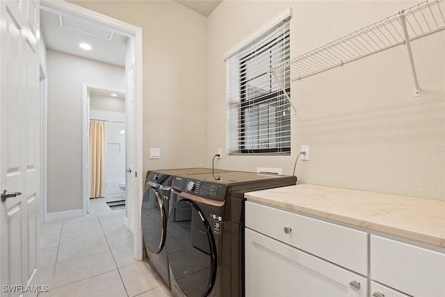 washroom featuring baseboards, cabinet space, light tile patterned floors, and washer and dryer