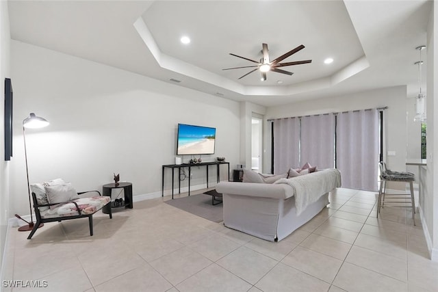 living room with a ceiling fan, baseboards, recessed lighting, light tile patterned floors, and a tray ceiling
