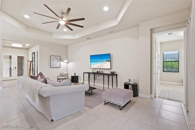 living room featuring ceiling fan, french doors, visible vents, a tray ceiling, and light tile patterned flooring