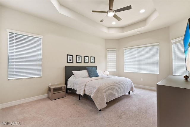bedroom featuring recessed lighting, a tray ceiling, light colored carpet, and baseboards