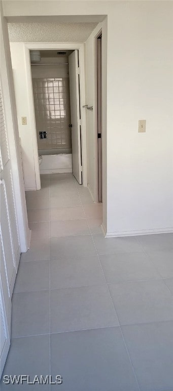 hallway with light tile patterned floors and baseboards