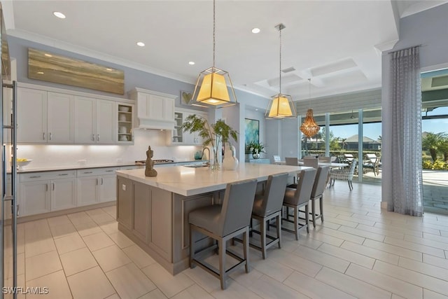 kitchen with pendant lighting, a kitchen breakfast bar, a kitchen island with sink, and white cabinets