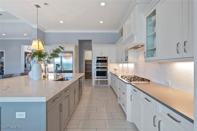 kitchen with tasteful backsplash, a sink, glass insert cabinets, stainless steel appliances, and white cabinetry