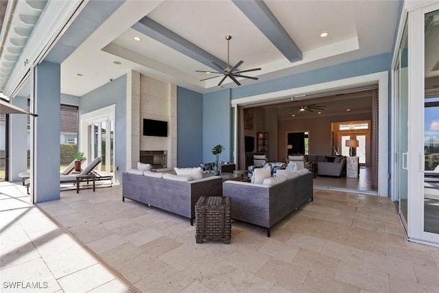 living area with recessed lighting, ceiling fan, a large fireplace, and a raised ceiling