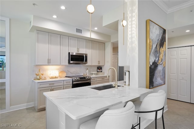 kitchen with a sink, light tile patterned floors, ornamental molding, and stainless steel appliances