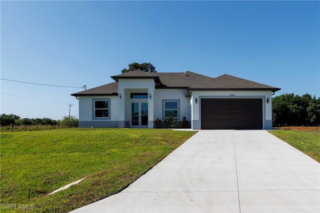 prairie-style home featuring driveway, french doors, a garage, a front lawn, and stucco siding
