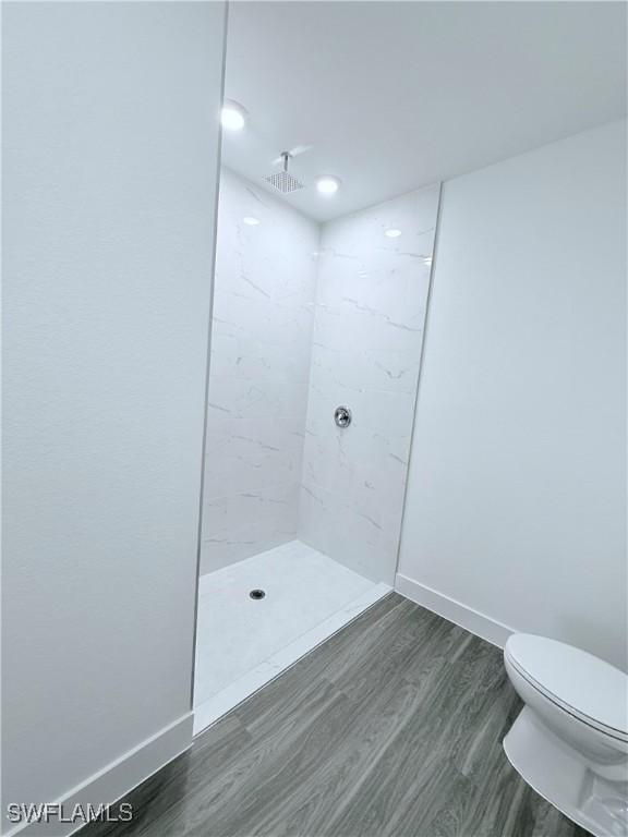5010 Day Ln, Labelle, FL 33935 - bathroom featuring baseboards, wood finished floors, toilet, and tiled shower