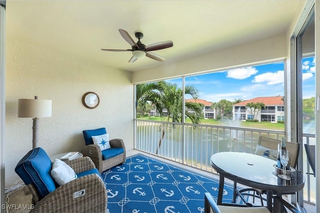 sunroom / solarium with a ceiling fan, a water view, and a wealth of natural light