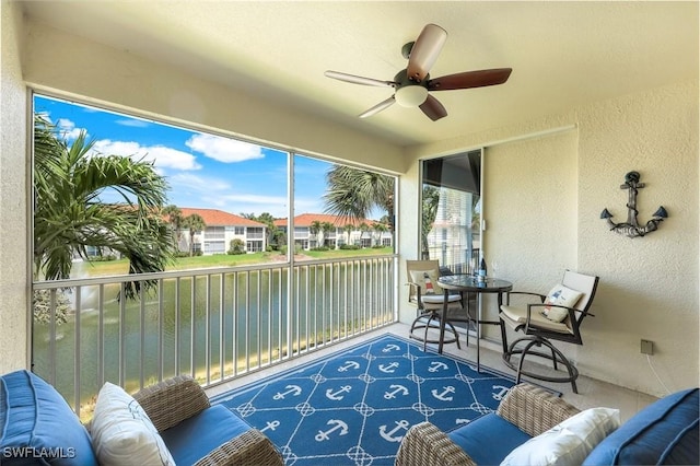sunroom with a water view, ceiling fan, an outdoor living space, and a residential view