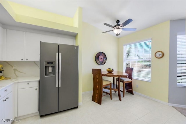 kitchen with light countertops, stainless steel refrigerator with ice dispenser, baseboards, and white cabinets