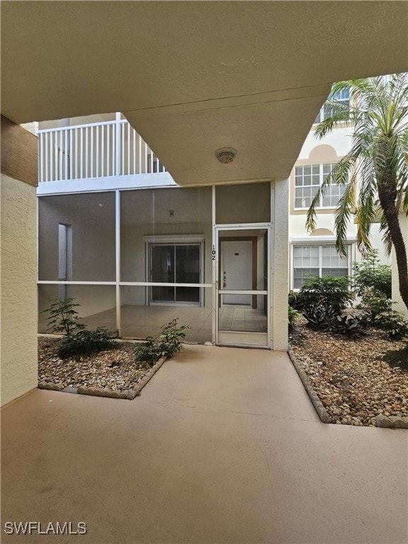 6025 Chardonnay Ln Unit 102, Naples, FL 34119 - doorway to property featuring stucco siding and a patio