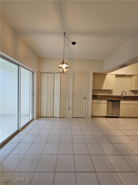 6025 Chardonnay Ln Unit 102, Naples, FL 34119 - kitchen with stainless steel dishwasher, dark countertops, decorative light fixtures, light tile patterned floors, and a sink