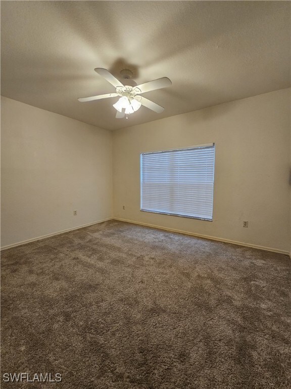 6025 Chardonnay Ln Unit 102, Naples, FL 34119 - empty room featuring carpet floors, a ceiling fan, and baseboards
