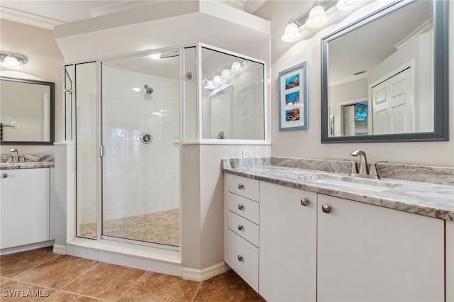full bath featuring crown molding, two vanities, a shower stall, and a sink