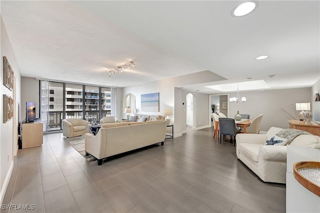 living room featuring an inviting chandelier, baseboards, and recessed lighting