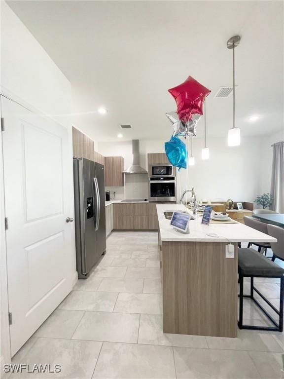 kitchen featuring wall chimney range hood, a sink, light countertops, stainless steel appliances, and modern cabinets