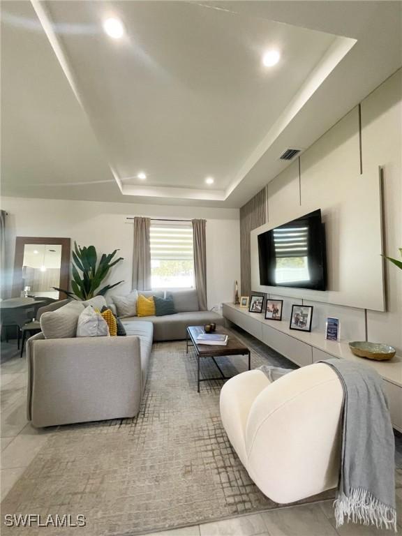 living area with visible vents, recessed lighting, and a raised ceiling