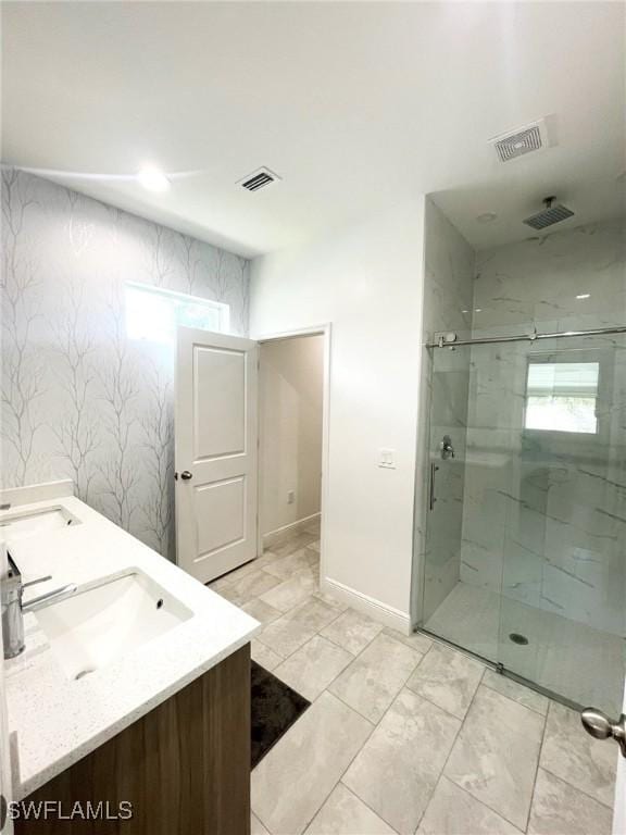 full bath with visible vents, a sink, a marble finish shower, and double vanity