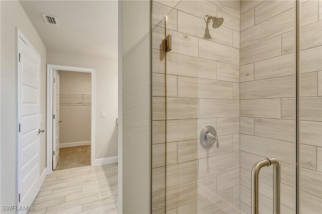 bathroom with baseboards, visible vents, a spacious closet, and a stall shower