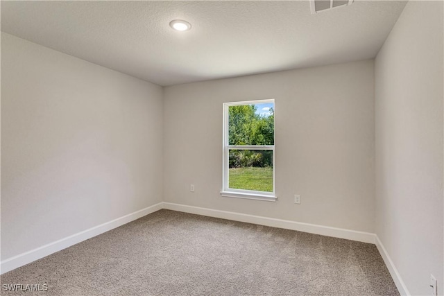 spare room featuring a textured ceiling, baseboards, visible vents, and carpet