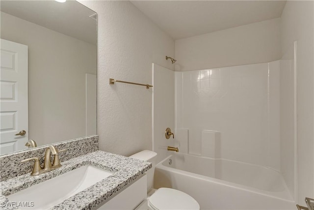 bathroom with vanity, a textured wall, bathing tub / shower combination, and toilet
