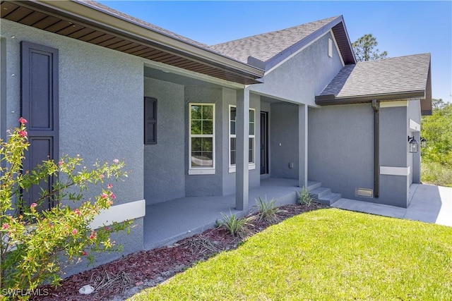 exterior space with a porch, roof with shingles, a front yard, and stucco siding