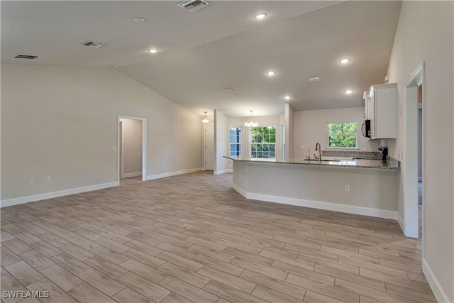 kitchen with a peninsula, visible vents, light wood finished floors, and lofted ceiling