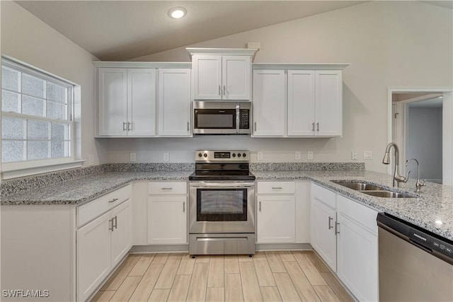 kitchen featuring a sink, white cabinetry, lofted ceiling, and stainless steel appliances