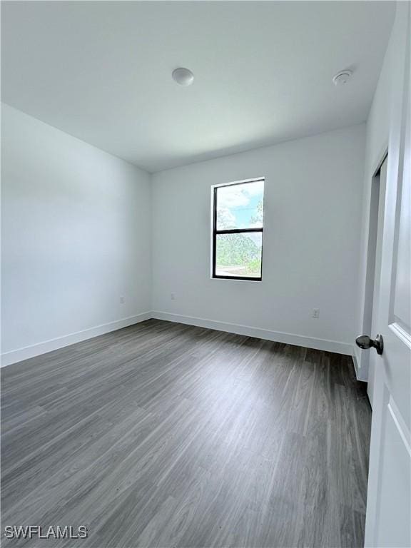 unfurnished bedroom featuring baseboards and dark wood-style flooring
