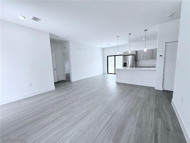 unfurnished living room featuring visible vents, baseboards, light wood-type flooring, recessed lighting, and a sink