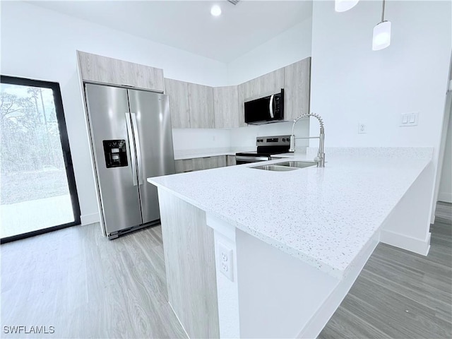 kitchen featuring appliances with stainless steel finishes, modern cabinets, light wood-type flooring, a sink, and a peninsula