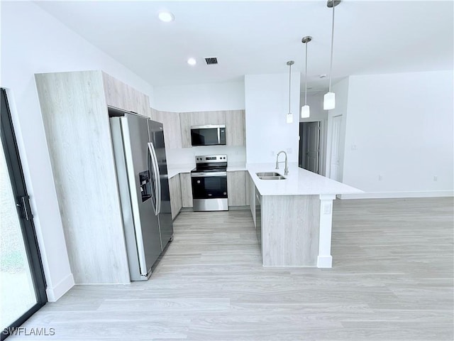 kitchen with appliances with stainless steel finishes, a sink, a peninsula, visible vents, and modern cabinets