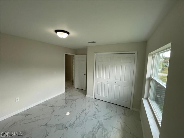 4709/4711 Leonard Blvd S, Lehigh Acres, FL 33973 - unfurnished bedroom with baseboards, light marble finish floors, and a closet
