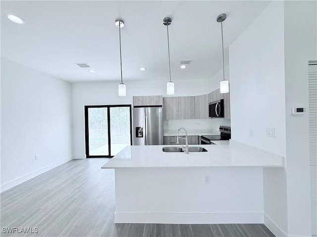kitchen with a peninsula, modern cabinets, light wood-type flooring, a sink, and appliances with stainless steel finishes