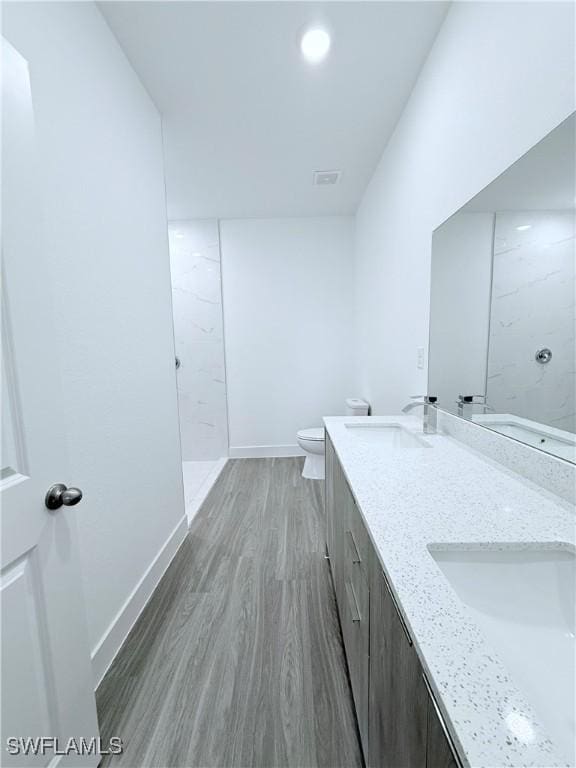 bathroom featuring baseboards, a sink, wood finished floors, and toilet