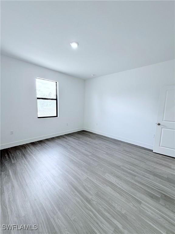 unfurnished room with baseboards and wood finished floors