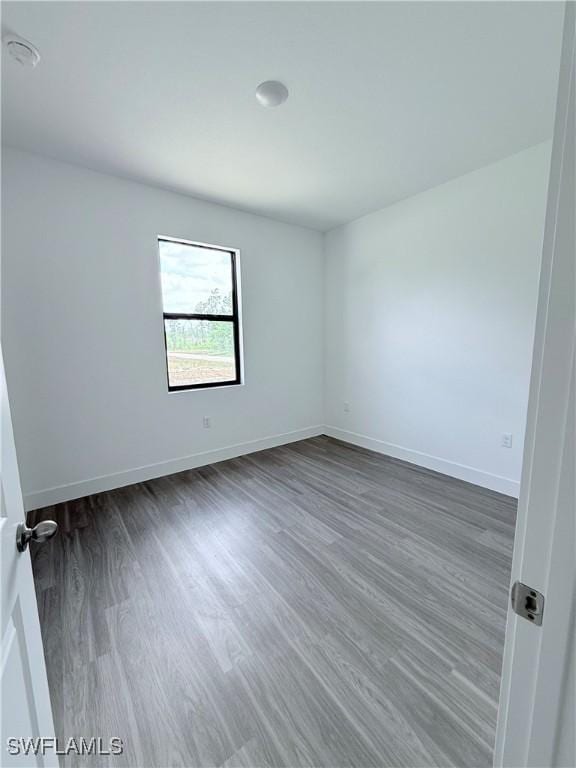 empty room with baseboards and dark wood-style floors