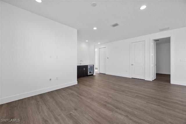 5243 Karlia Dr, Ave Maria, FL 34142 - unfurnished living room featuring visible vents, dark wood-style flooring, baseboards, beverage cooler, and recessed lighting