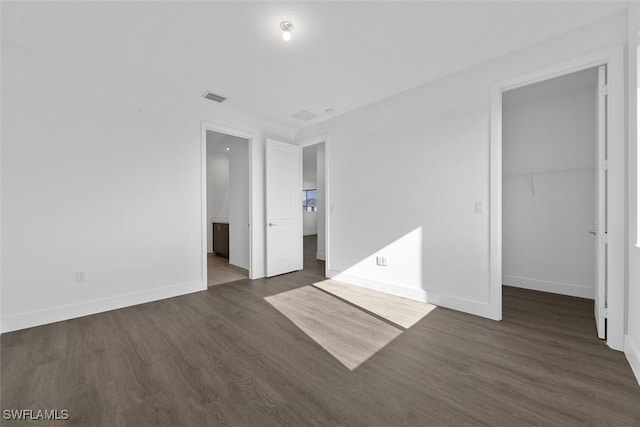 5243 Karlia Dr, Ave Maria, FL 34142 - unfurnished bedroom with visible vents, a closet, baseboards, a walk in closet, and dark wood finished floors