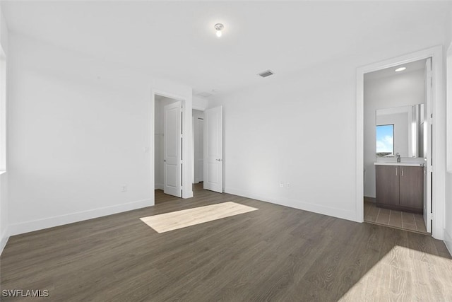 5243 Karlia Dr, Ave Maria, FL 34142 - unfurnished bedroom featuring dark wood-style flooring, visible vents, a sink, baseboards, and connected bathroom