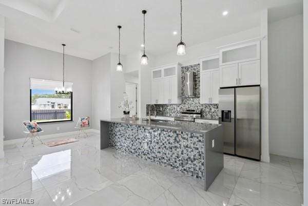 kitchen with stainless steel refrigerator with ice dispenser, wall chimney exhaust hood, light marble finish floors, white cabinets, and tasteful backsplash