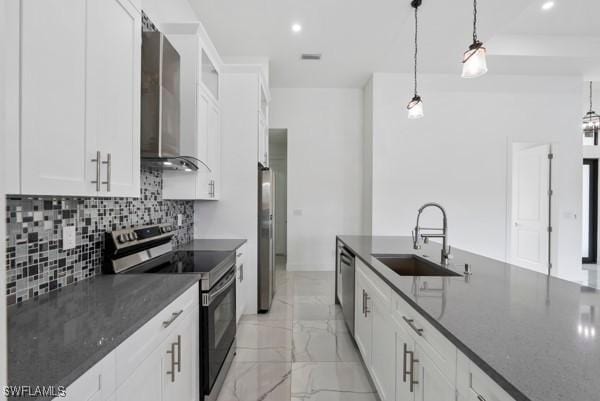 kitchen with stainless steel appliances, a sink, wall chimney exhaust hood, backsplash, and white cabinets
